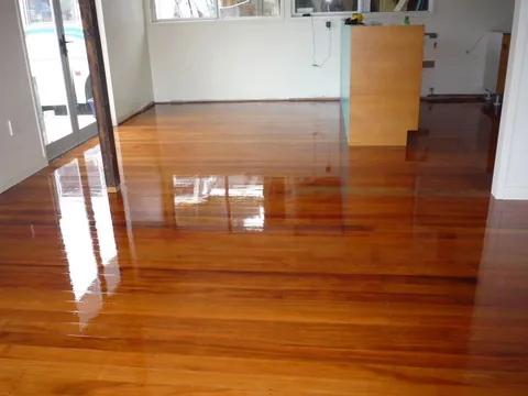 Newly finished rimu floor in an empty open-plan room, window light reflecting in long streaks across the boards